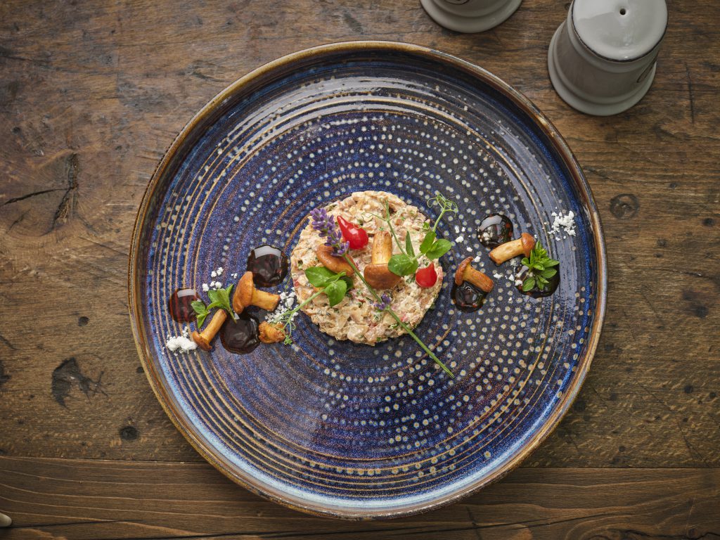 Chanterelle tartare with vegetables arranged on a blue plate