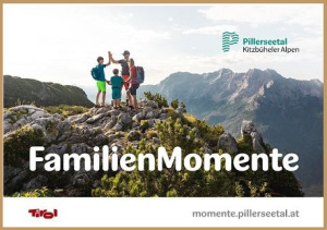 Zwei Erwachsene und zwei Kinder stehen auf einem felsigen Berggipfel vor Alpenpanorama; Schriftzug „FamilienMomente“