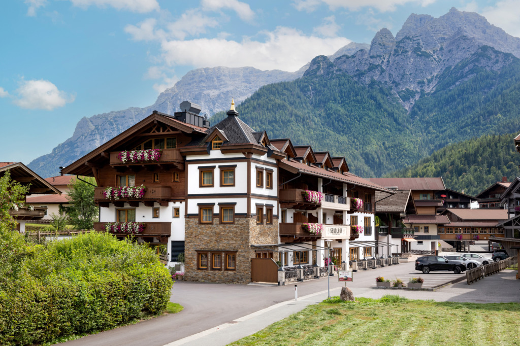 Hotel Sendlhof mit blumengeschmückten Balkonen vor bewaldeter Bergkulisse